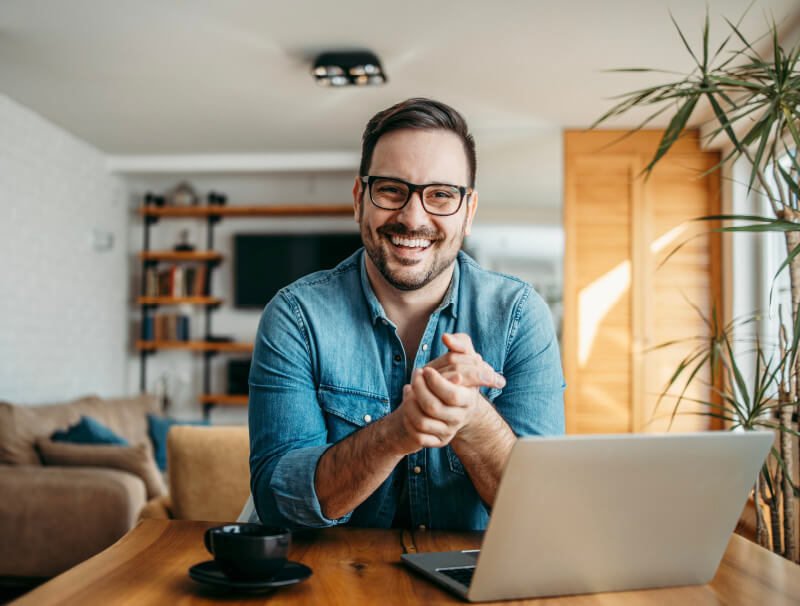 man smiling while using services on laptop