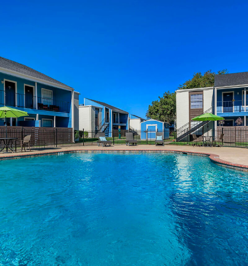 view of pool between blue apartment buildings