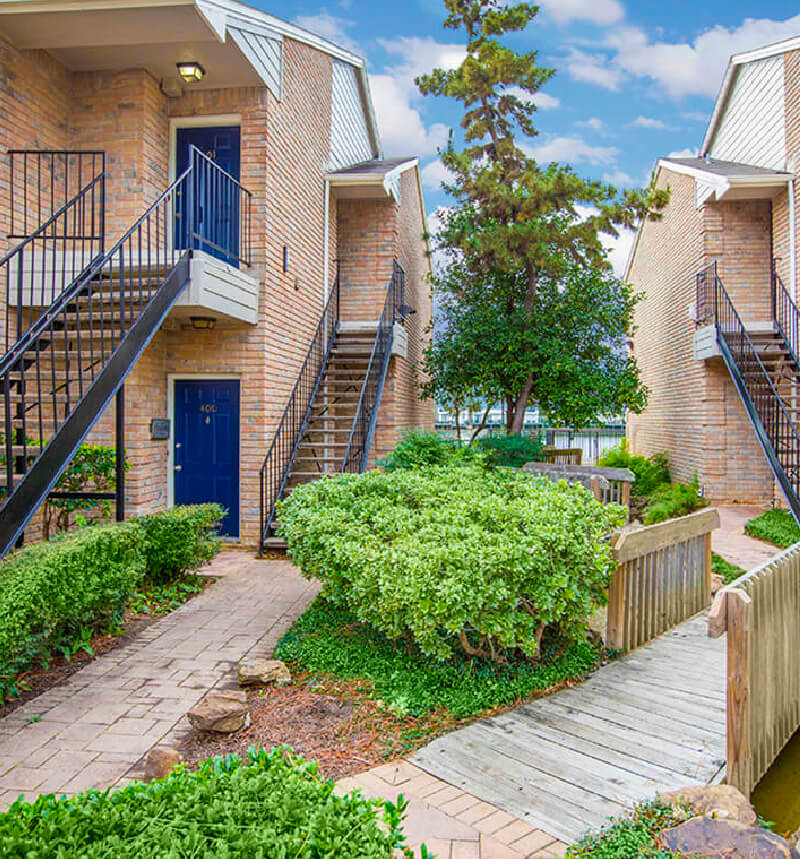 nice green trees and bushes surround brick sided apartments